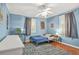 Comfortable bedroom featuring blue walls, wood floors, and a ceiling fan with lighting at 877 Mclendon Dr, Scottdale, GA 30079