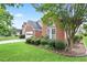 Beautiful landscaping frames the front of this classic brick home and driveway on a sunny day at 1460 Chamirey Sw Dr, Marietta, GA 30008