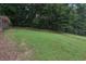 The grassy backyard hill has a partial fence and tree line on a sunny day at 2784 Oxford Dr, Decatur, GA 30034