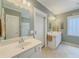 Bright bath with double sinks, glass block window, and shower behind a glass door at 557 Pringle Dr, Suwanee, GA 30024