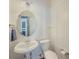 Stylish powder room with pedestal sink, round mirror, and decorative accents at 557 Pringle Dr, Suwanee, GA 30024