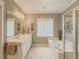 Bathroom featuring soaking tub, glass block window, and a framed mirror over double sinks at 557 Pringle Dr, Suwanee, GA 30024