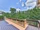 Spacious wooden deck with railing overlooking lush green trees and a blue sky with clouds at 310 River Birch Ct, Canton, GA 30114