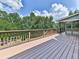 Large deck with wood railing offering serene views of the surrounding trees and partial view of a screened-in porch at 310 River Birch Ct, Canton, GA 30114