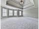 Expansive primary bedroom with tray ceiling, carpeting, and plenty of natural light at 310 River Birch Ct, Canton, GA 30114