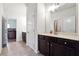 Hall bathroom with white countertops and dark cabinetry, and view into a bedroom with wood floors at 1730 Dahlia Dr, Cumming, GA 30040