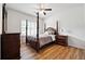 This bright bedroom includes wood floors, a four-poster bed, side table, dresser, and a ceiling fan at 1730 Dahlia Dr, Cumming, GA 30040