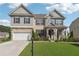 Charming two-story home featuring brick, stone accents, a manicured lawn, and an attached two-car garage at 1730 Dahlia Dr, Cumming, GA 30040