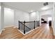 Upstairs hallway featuring wood floors, wood railing, and views of bedrooms at 1730 Dahlia Dr, Cumming, GA 30040