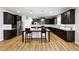 Modern kitchen featuring dark cabinets, stainless steel appliances, a large island, and wood flooring at 1730 Dahlia Dr, Cumming, GA 30040