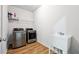 Laundry room featuring stainless steel washer/dryer, utility sink, and wood flooring at 1730 Dahlia Dr, Cumming, GA 30040