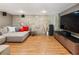 Basement with a stone wall, entertainment center, gray sectional, and hardwood flooring for a cozy space at 1164 Bonview Ne Ln, Atlanta, GA 30324