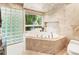 Bright bathroom featuring a soaking tub, tiled walls, and a window with views of the trees at 1164 Bonview Ne Ln, Atlanta, GA 30324