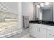 Vanity with a framed mirror, dark countertop, and modern lighting fixtures next to a window at 1967 Cogar Dr, Decatur, GA 30032