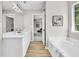 Bright bathroom featuring a soaking tub, a shower, double vanity sinks, and wood-look flooring at 2720 Meridian Ct, Dacula, GA 30019