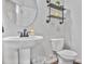 Small powder room featuring open shelving, round mirror, pedestal sink, white toilet and dark wood flooring at 3586 Maple Hill Rd, Stonecrest, GA 30038