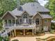 Back of house featuring multiple decks, patios, manicured landscaping, and large windows providing natural light at 407 Amber Ln, Woodstock, GA 30189