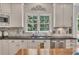 Kitchen with white cabinets, sink, black countertop, stainless dishwasher, and decorative backsplash at 407 Amber Ln, Woodstock, GA 30189