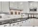 Close-up of gas cooktop with microwave and decorated backsplash at 407 Amber Ln, Woodstock, GA 30189