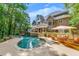 Backyard pool and patio area with waterfall feature on a luxury home surrounded by mature trees and landscaping at 407 Amber Ln, Woodstock, GA 30189