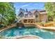 Backyard of a large house with a pool, stone waterfall, and outdoor living space surrounded by mature trees at 407 Amber Ln, Woodstock, GA 30189