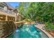 Large gunite pool with stone waterfall, lush landscaping, and ample patio space surrounded by trees and greenery at 407 Amber Ln, Woodstock, GA 30189