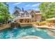 Backyard pool and patio area with waterfall feature on a luxury home surrounded by mature trees and landscaping at 407 Amber Ln, Woodstock, GA 30189