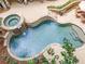 Aerial view of the uniquely shaped stone pool with attached hot tub, water feature, and beautiful landscaping at 407 Amber Ln, Woodstock, GA 30189