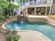 Stone pool with waterfall feature, surrounded by lush landscaping, and an elevated patio area for relaxing and entertaining at 407 Amber Ln, Woodstock, GA 30189