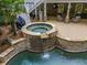 Stone hot tub with waterfall, landscaping, and access to the covered patio area at 407 Amber Ln, Woodstock, GA 30189