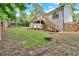 Wide backyard view, showcasing the wooden deck with stairs, partially fenced yard, and mature trees at 6918 Heritage Pl, Acworth, GA 30102