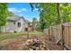 Large, partially fenced backyard with a wooden deck, fire pit, and mature trees creating a private space at 6918 Heritage Pl, Acworth, GA 30102