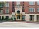 Close up of building entrance with golden doors and trim, featuring stone accents and manicured landscaping at 77 Peachtree Ne Pl # 101, Atlanta, GA 30309