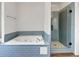 Modern bathroom features a soaking tub with blue tile accents, and a frameless glass shower at 110 Wyngate Way, Fayetteville, GA 30215