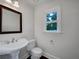 Bright powder room with pedestal sink, large framed mirror, and ample natural light at 110 Wyngate Way, Fayetteville, GA 30215