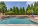 Beautiful backyard pool with a stone waterfall feature surrounded by lush landscaping and mature trees at 120 Slate Dr, Buford, GA 30518