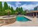Gorgeous swimming pool and jacuzzi surrounded by stone patio and lush trees, with screened-in porch at 120 Slate Dr, Buford, GA 30518