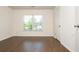 A well-lit bedroom featuring hardwood floors, a window, and a white door at 4583 Grenadine Cir, Acworth, GA 30101