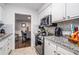 Compact kitchen featuring granite countertops, white cabinets, stainless appliances and access to dining room at 46 Le Parc Fontaine, Lithonia, GA 30038