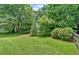 Lush green backyard with manicured lawn, mature trees, and partial fencing at 328 West Ln, Woodstock, GA 30188