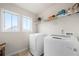 Functional laundry room featuring side-by-side washer and dryer, windows, and overhead shelving at 3291 Meadow Lily Ct, Buford, GA 30519