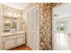 Retro bathroom features a single vanity with a mirror, flowered wallpaper, and a view into the bedroom at 3623 Doroco Dr, Atlanta, GA 30340