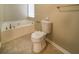Bright bathroom featuring a soaking tub, toilet, and neutral tile flooring at 5958 Tate Dr, Austell, GA 30106