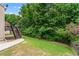 Backyard with a grassy lawn, wooden deck with stairs, and mature trees in the background at 871 Windsor Creek Dr, Grayson, GA 30017