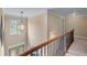 Bright upstairs hallway with decorative light fixture and staircase with wooden and iron railing at 871 Windsor Creek Dr, Grayson, GA 30017