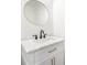 Elegant bathroom vanity with marble countertop, stylish fixtures, and a round mirror at 1454 Rome Nw Dr, Atlanta, GA 30314