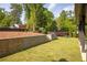 Well-manicured backyard featuring a retaining wall, lush lawn, and seating area surrounded by mature trees at 2469 River Oak Dr, Decatur, GA 30033