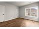 Bright bedroom featuring hardwood floors, a large window, and two doors with modern black hardware at 6750 Pannell Rd, Buford, GA 30518