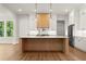 Bright kitchen features a large center island, modern light fixtures, stainless steel appliances and white cabinets at 6750 Pannell Rd, Buford, GA 30518