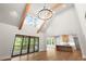 Living room view, showcasing high ceilings, wood beams, sliding glass doors, and a glimpse of the kitchen at 6750 Pannell Rd, Buford, GA 30518